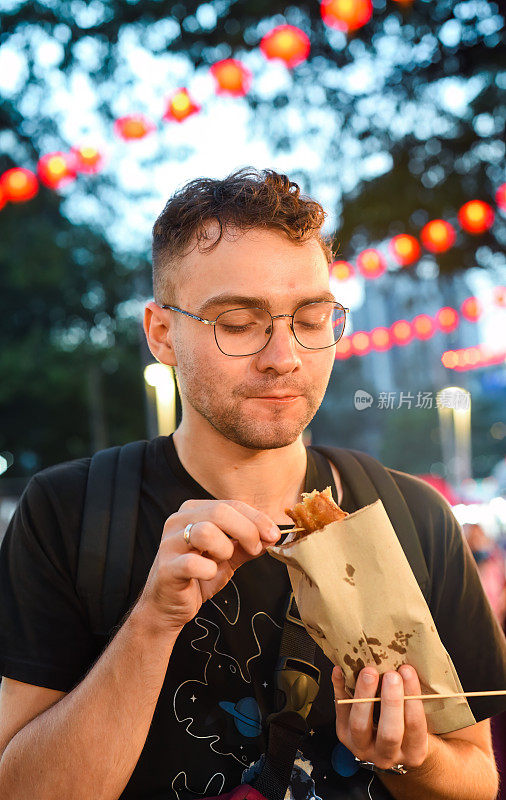 马来西亚吉隆坡，一名年轻游客在Jalan Alor街头小吃吃炸香蕉
